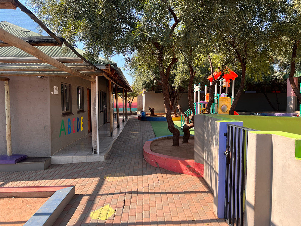 The walkway beside the classrooms, with ABCDE painted on the wall and the playground beyond