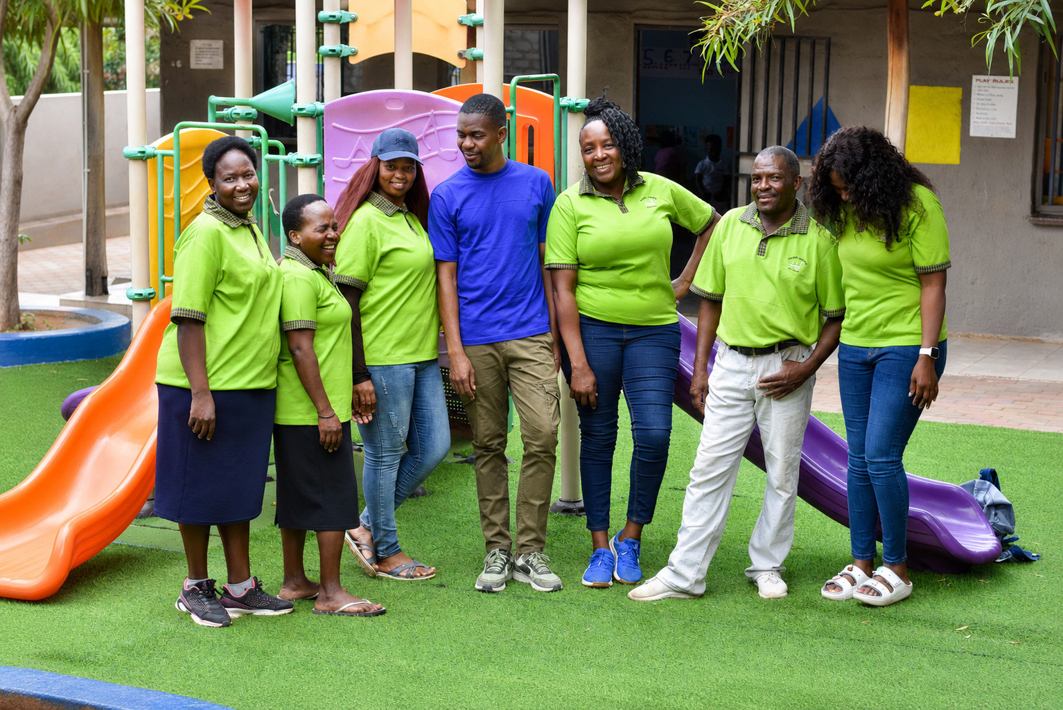 The Zonke Izizwe staff standing together on the playground in their green shirts